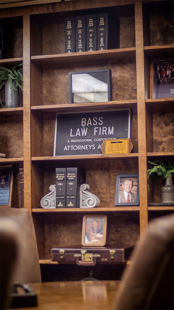 Bass Law Firm metal sign on the bookshelf with books, photos, and plants
